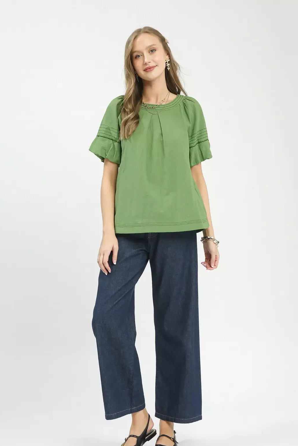 Woman wearing a green top and blue pants on a white background
