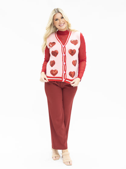 Woman wearing a red and white heart-patterned sweater with matching pants on a white background