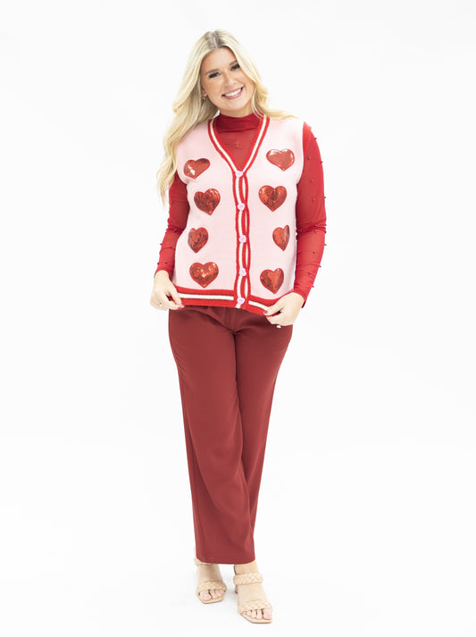 Woman wearing a red and white heart-patterned sweater with matching pants on a white background