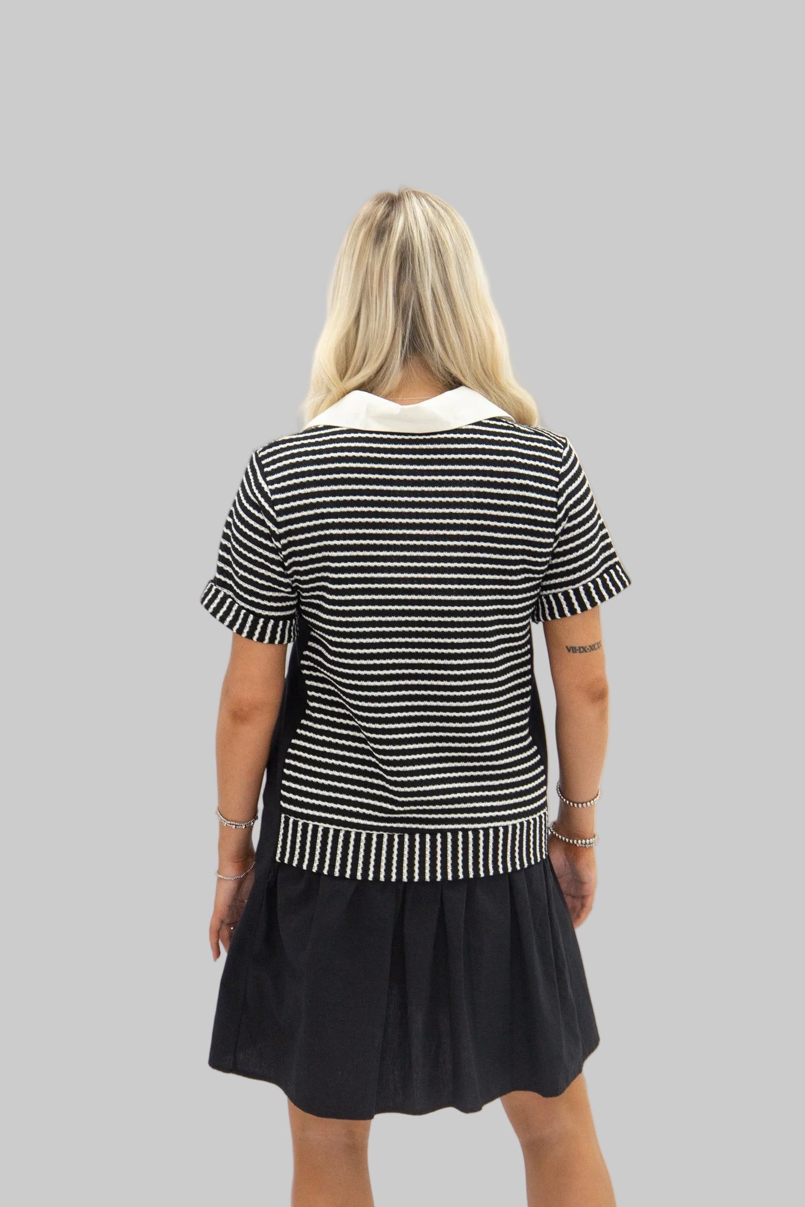 Woman wearing a black and white striped dress with a white collar on a white background