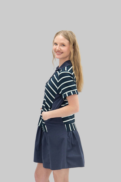 Woman wearing a navy and white striped dress with a navy skirt on a white background