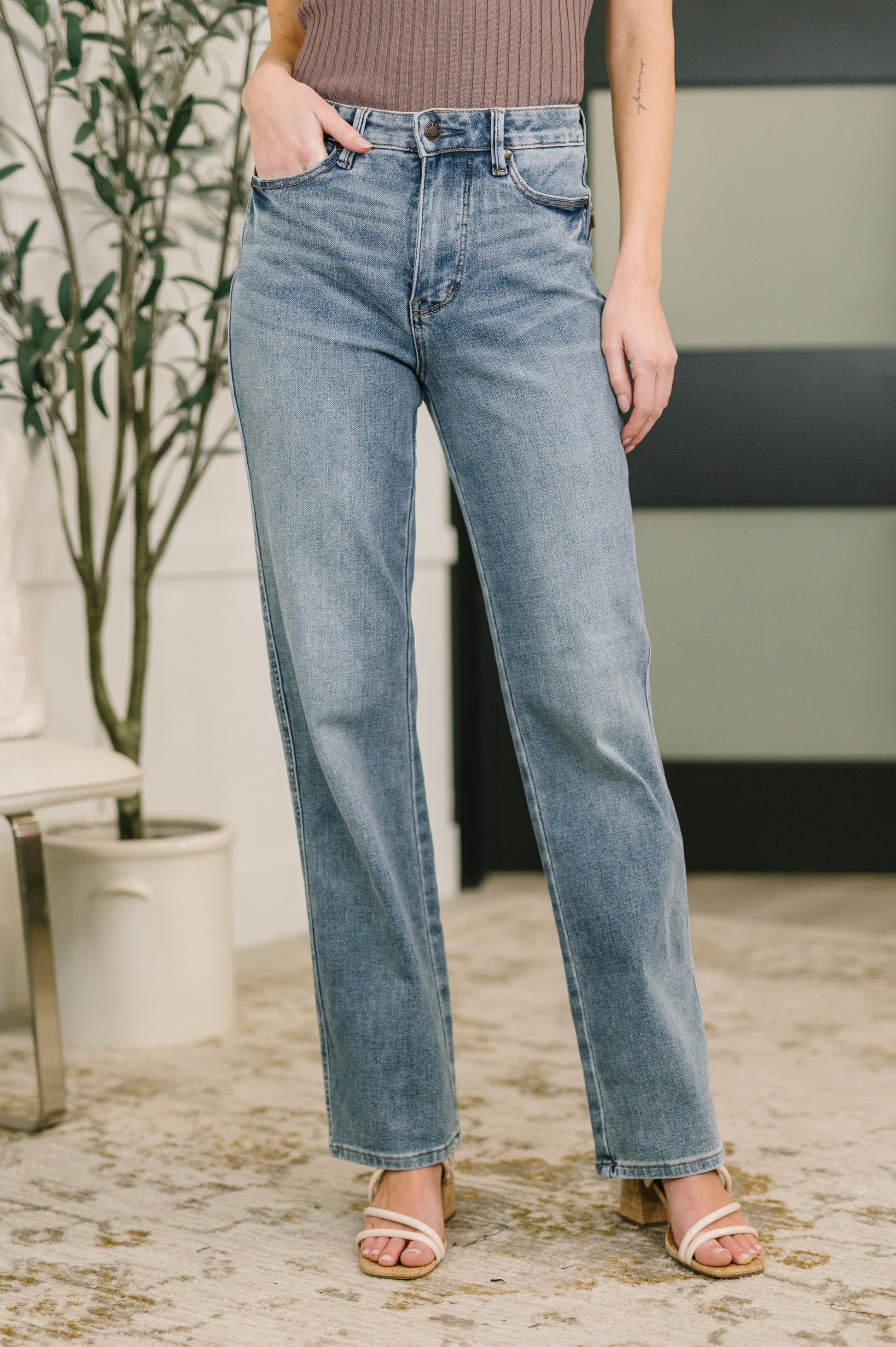 Person wearing light blue jeans standing indoors with a blurred background