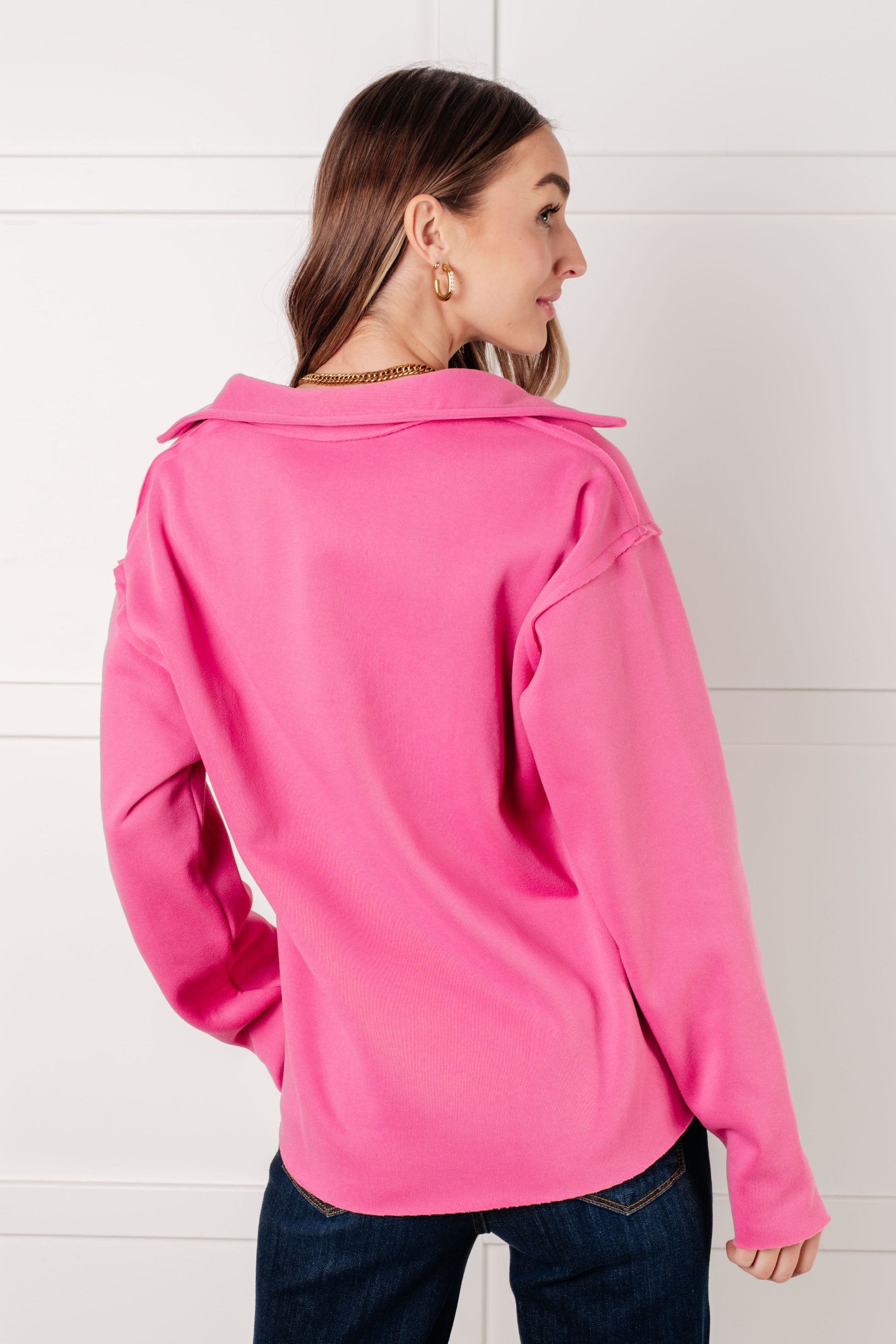 Woman wearing a bright pink jacket with a hood against a white background