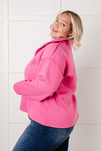 Person wearing a bright pink coat against a white tiled wall