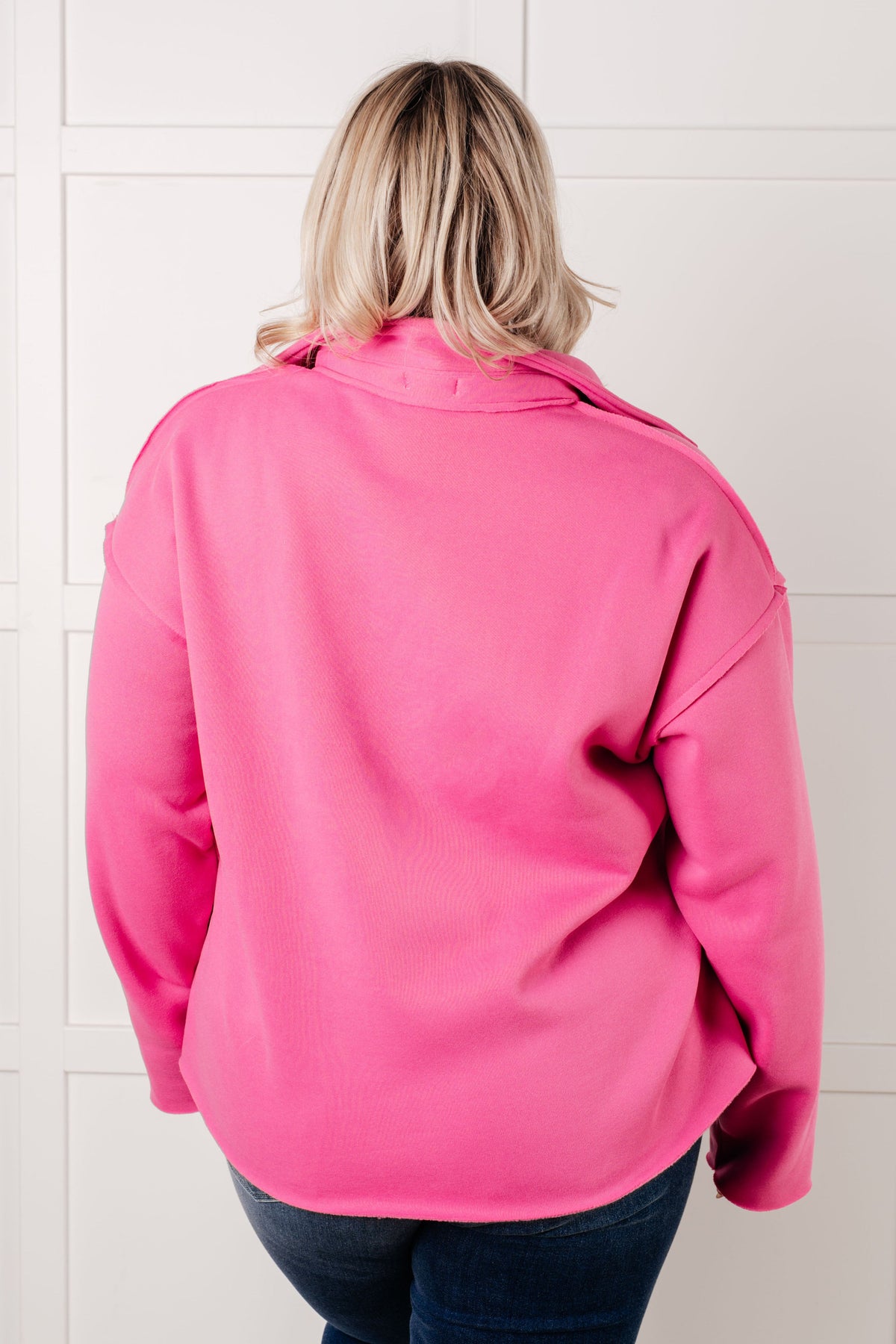 Person wearing a bright pink jacket in front of a tiled wall