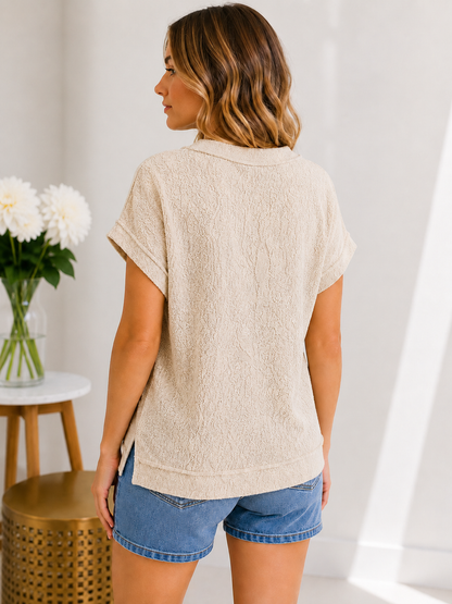 Woman wearing a beige textured top and blue shorts in a bright room.