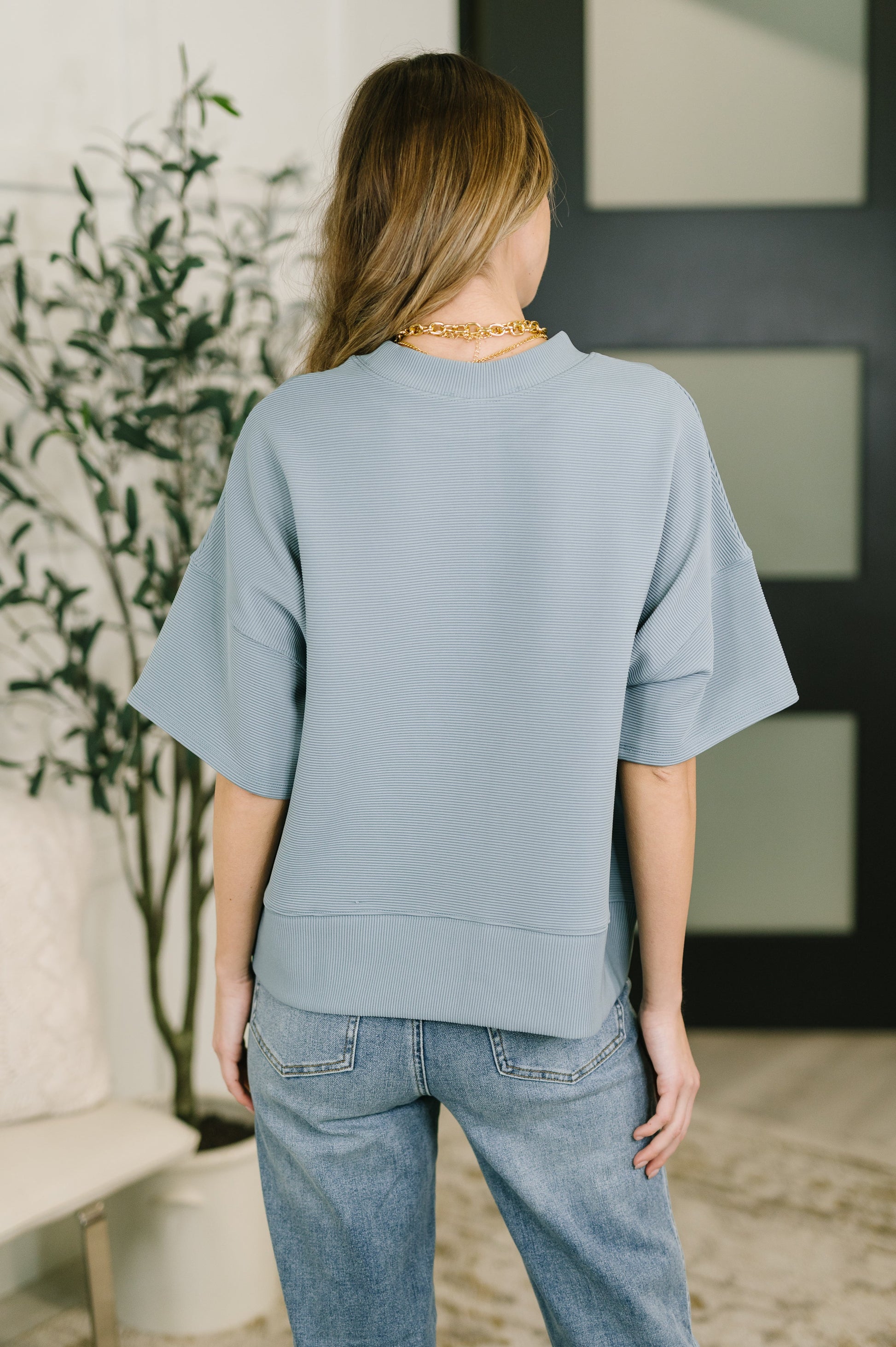 Person wearing a light blue sweater and jeans in an indoor setting