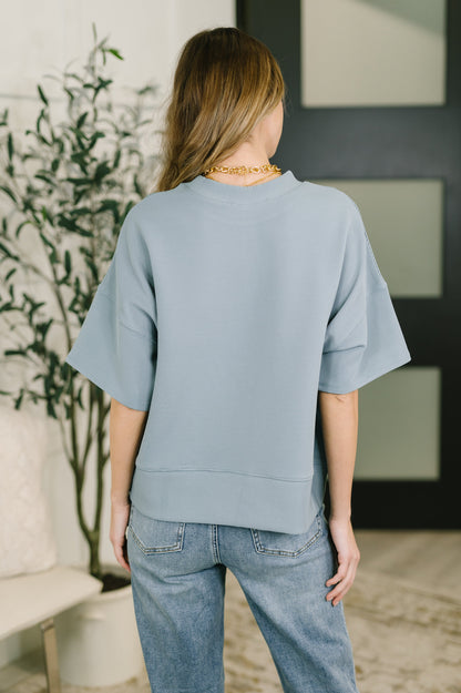 Person wearing a light blue sweater and jeans in an indoor setting