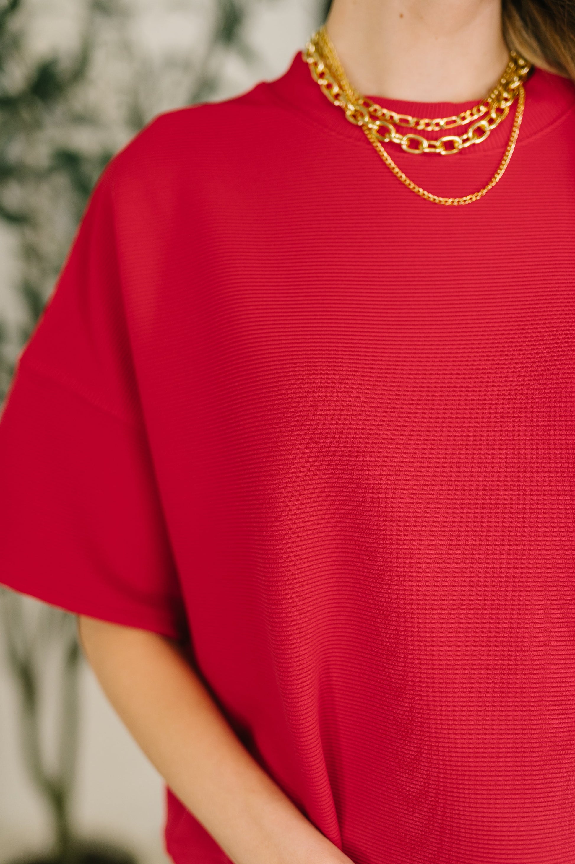 Red top worn by a person with a blurred background