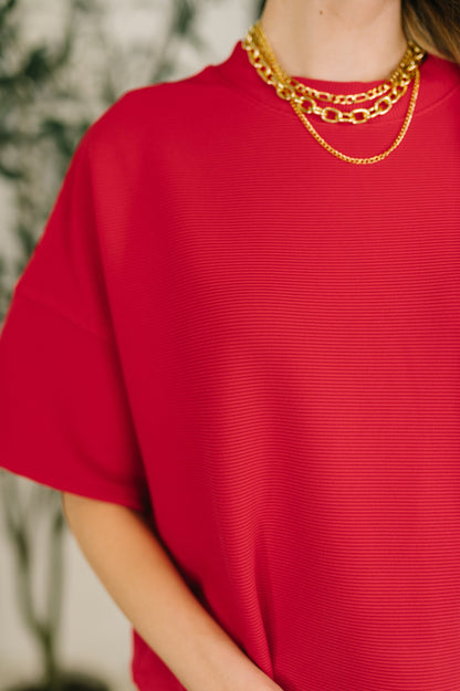 Red top worn by a person with a blurred background