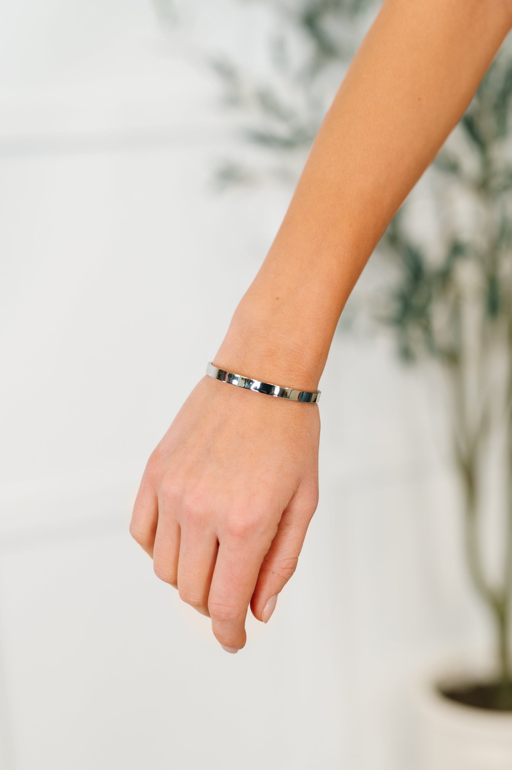Hand wearing a silver bracelet with a blurred background