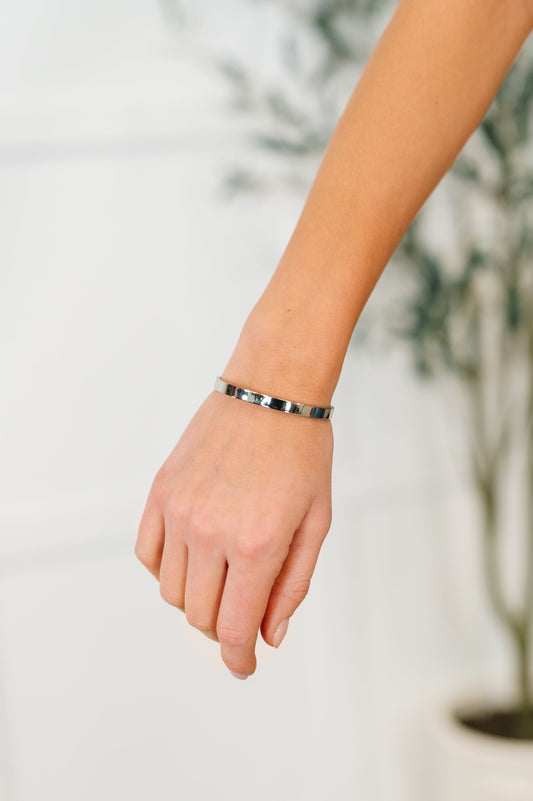 Hand wearing a silver bracelet with a blurred background