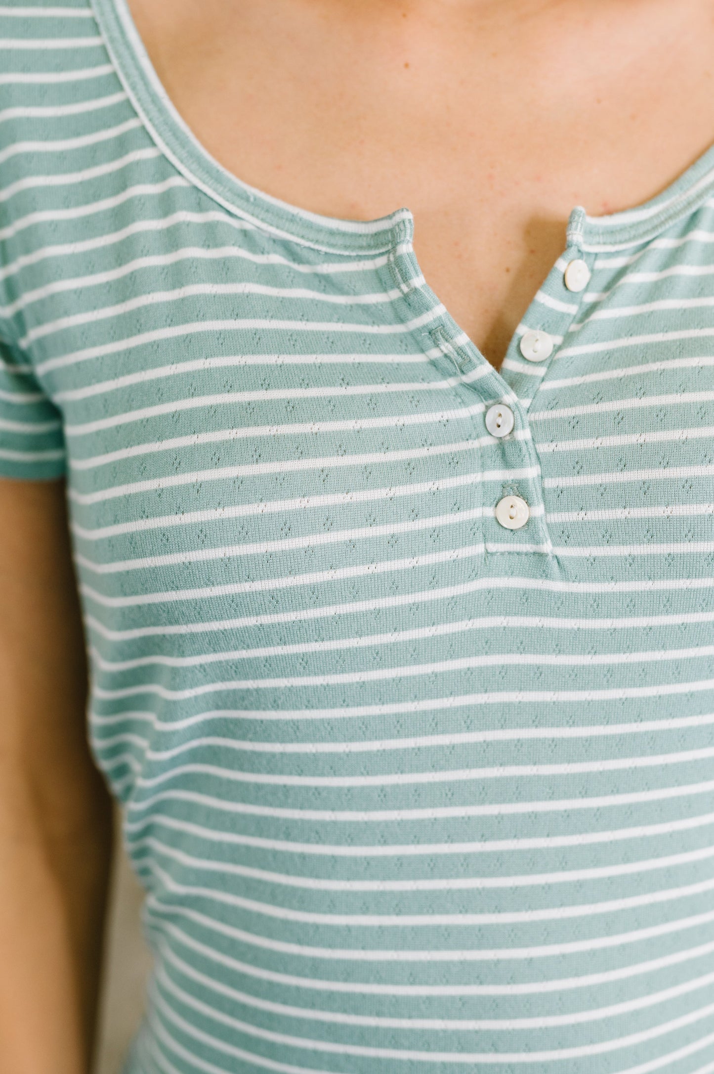 Close-up of a person wearing a green and white striped shirt with buttons.