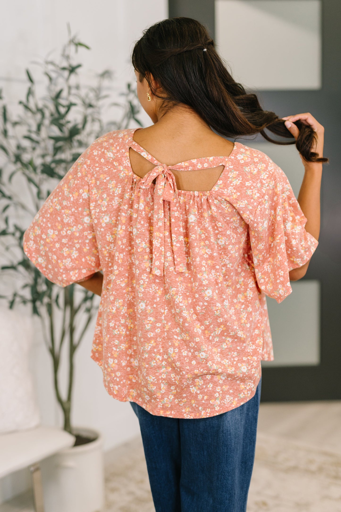 Woman wearing a pink floral blouse with a blurred indoor background
