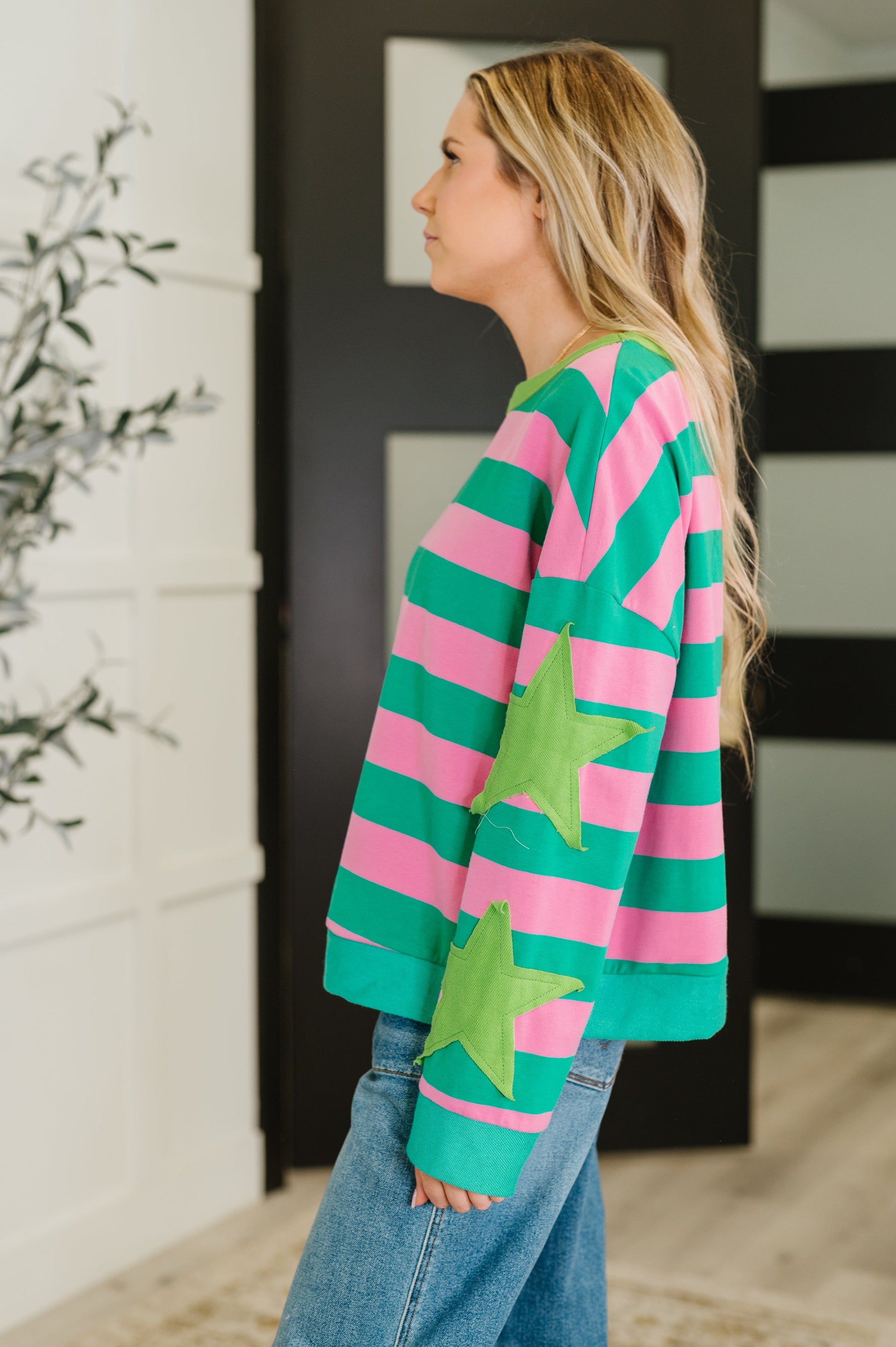 Person wearing a colorful striped sweater with green stars indoors.