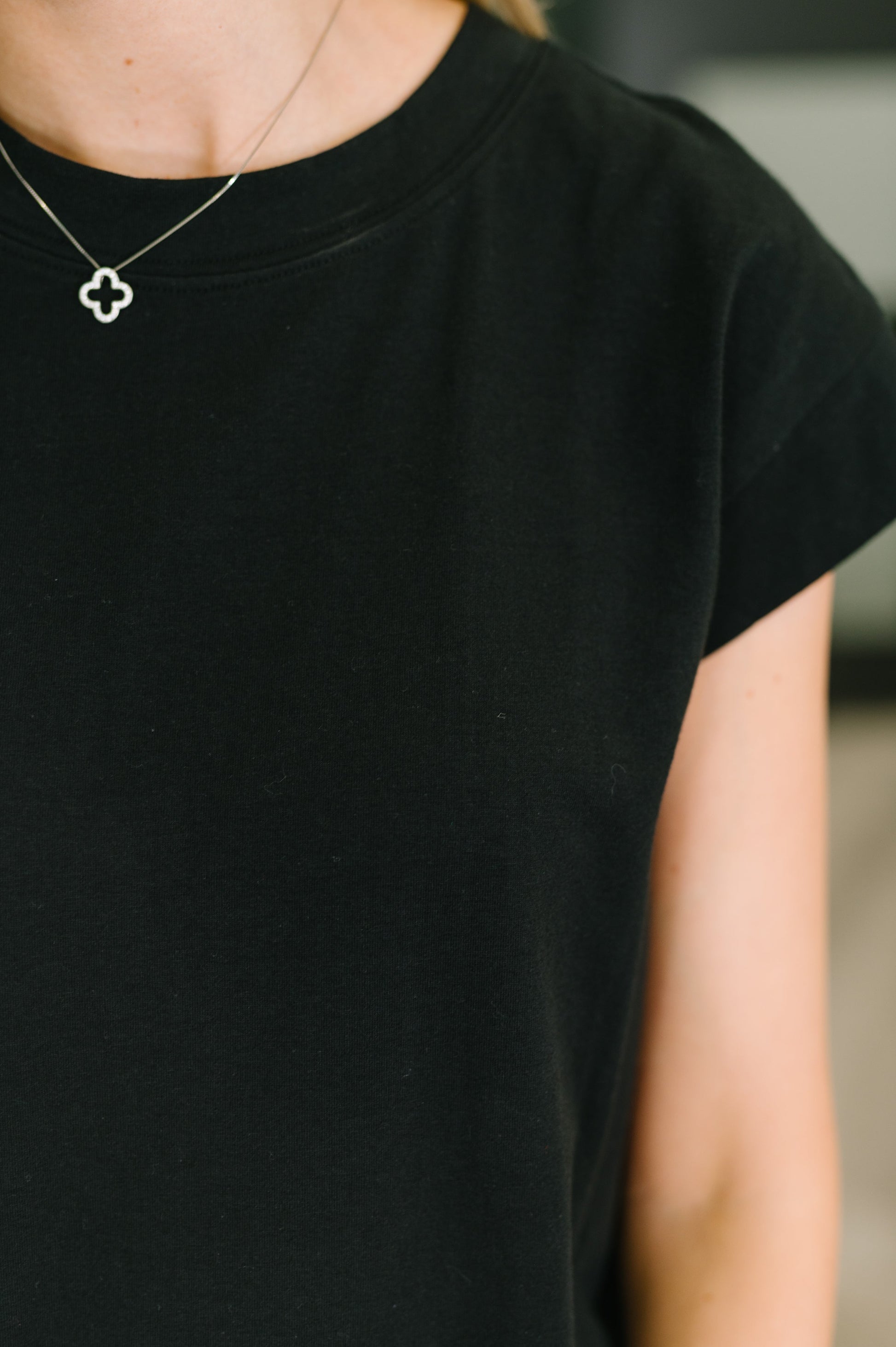 Person wearing a black t-shirt with a blurred background