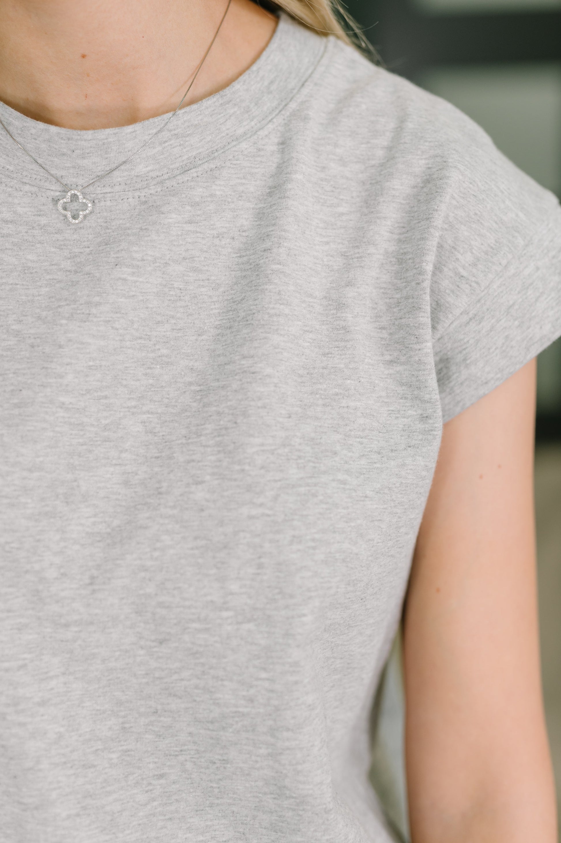 Person wearing a gray t-shirt with a blurred background