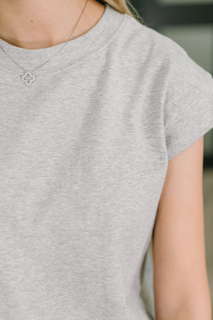 Person wearing a gray t-shirt with a blurred background