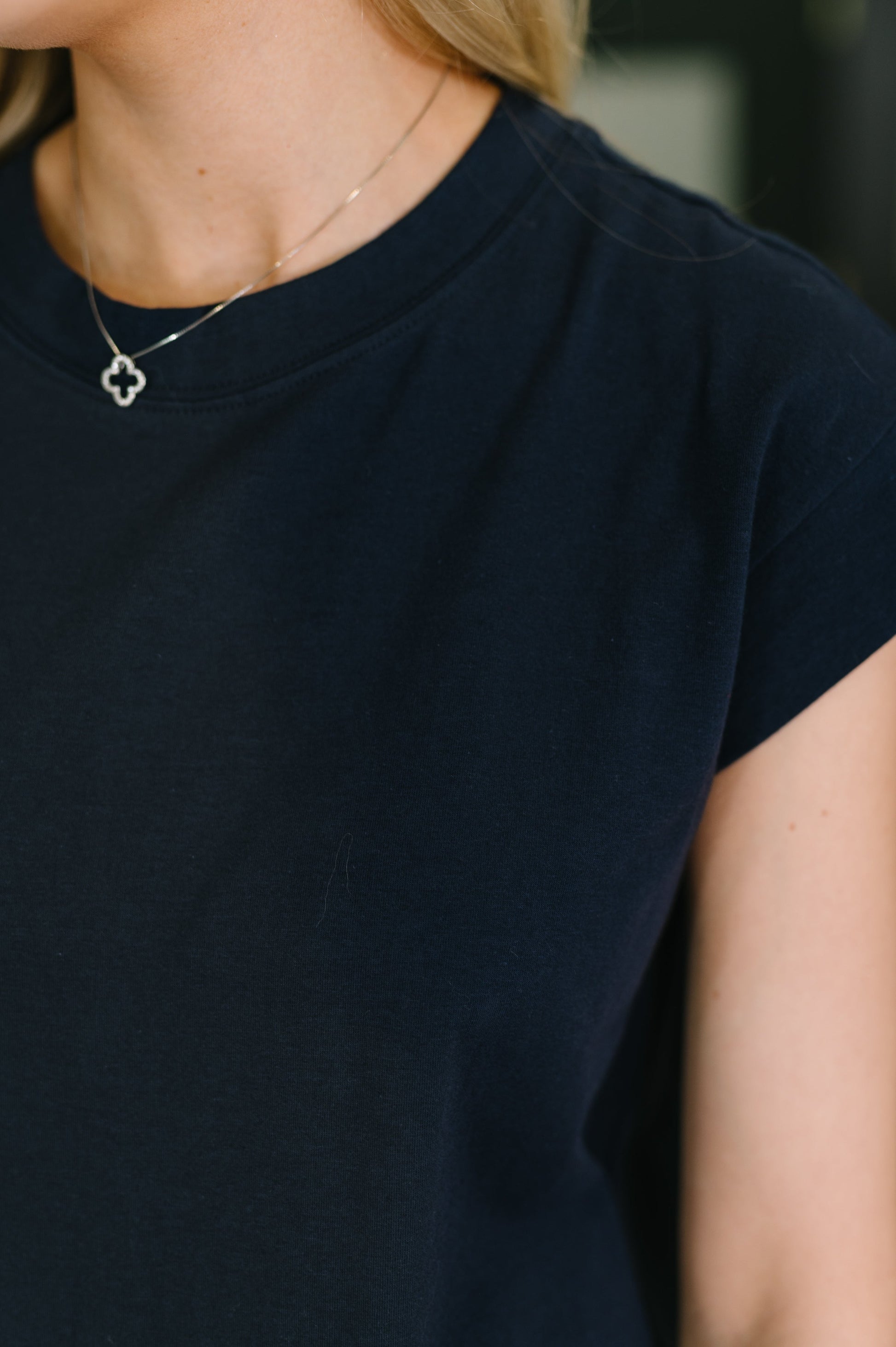Person wearing a dark blue t-shirt with a blurred background