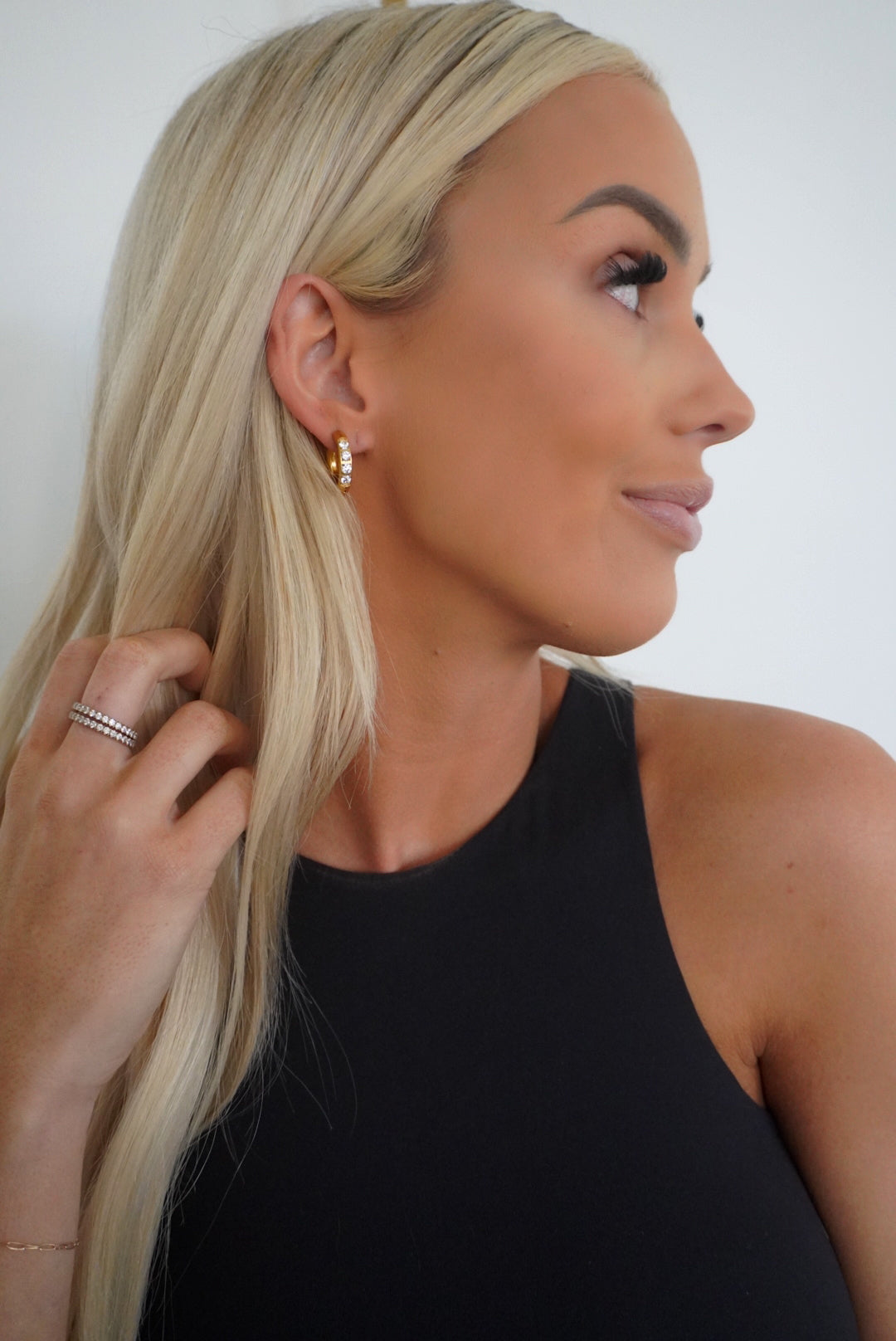 Woman adjusting her blonde hair against a white background
