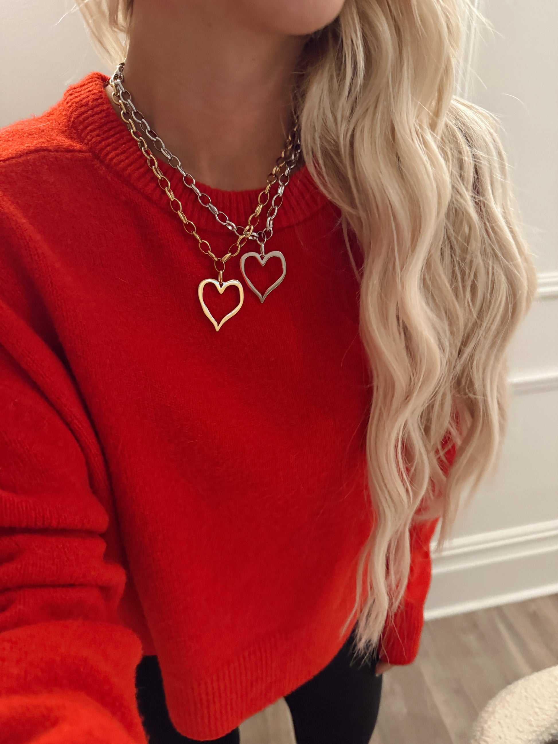Person wearing a red sweater with a gold heart-shaped necklace