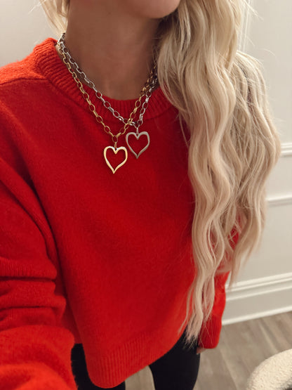 Person wearing a red sweater with a gold heart-shaped necklace