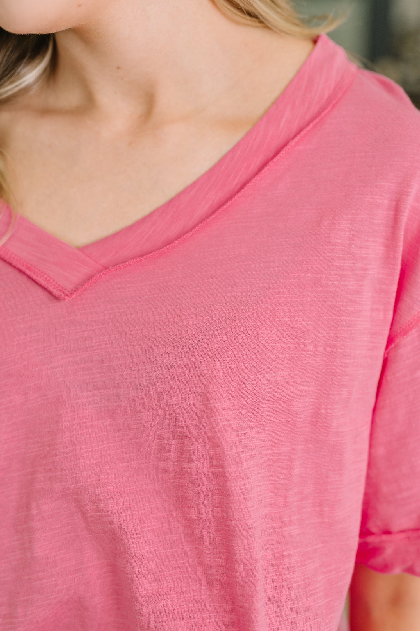 Close-up of a person wearing a pink shirt with a blurred background