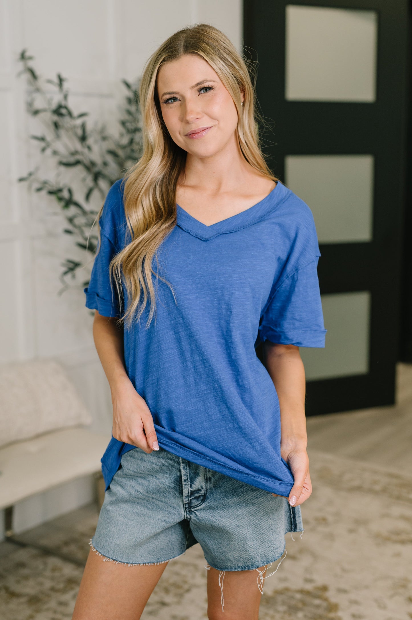 Woman wearing a blue shirt and denim shorts indoors