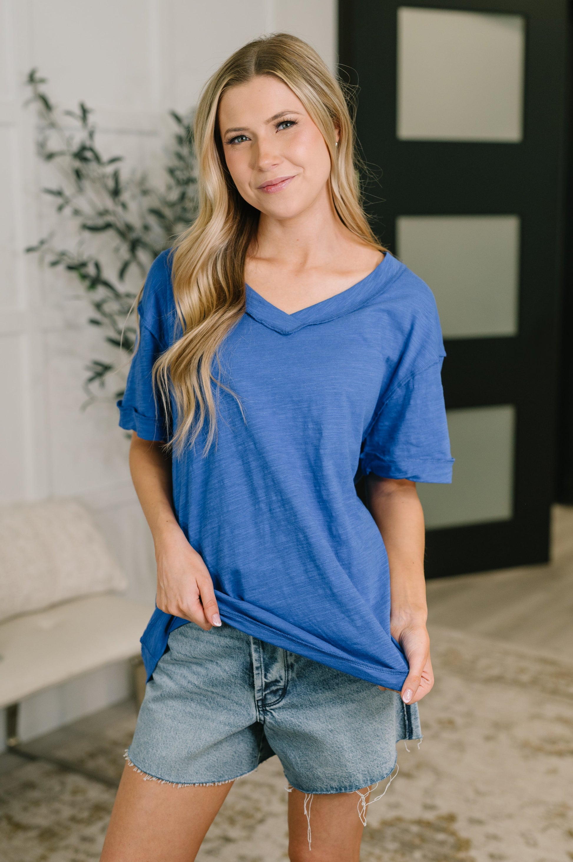Woman wearing a blue shirt and denim shorts indoors