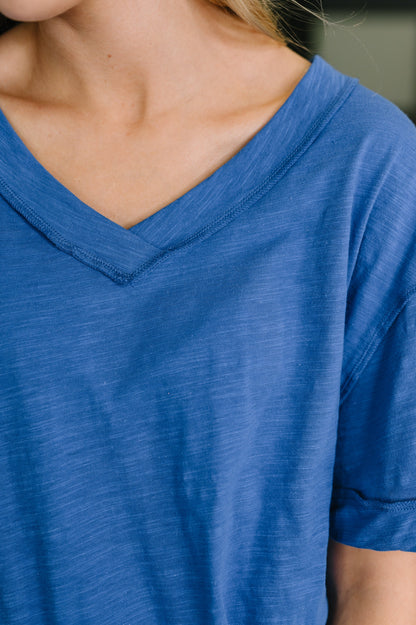 Close-up of a person wearing a blue V-neck shirt.