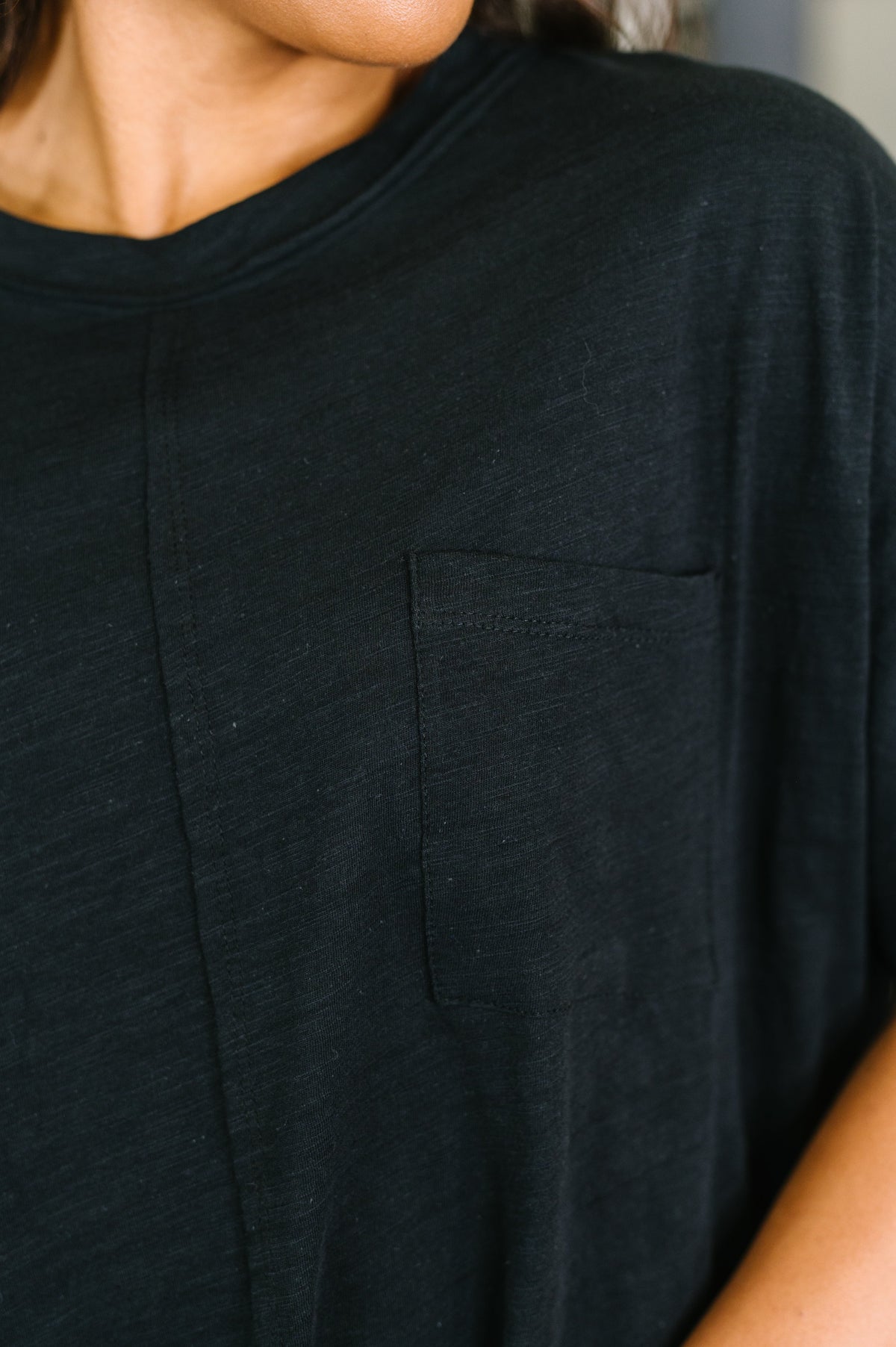Close-up of a person wearing a black short-sleeve crewneck t-shirt with a chest pocket.