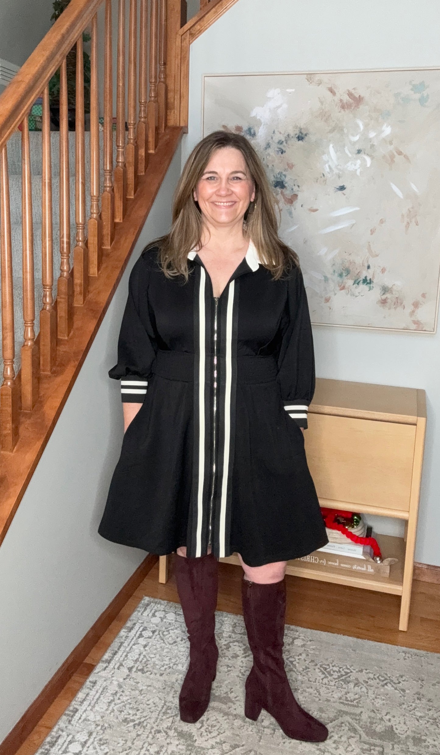 Woman in a black dress with white stripes standing in a home setting.
