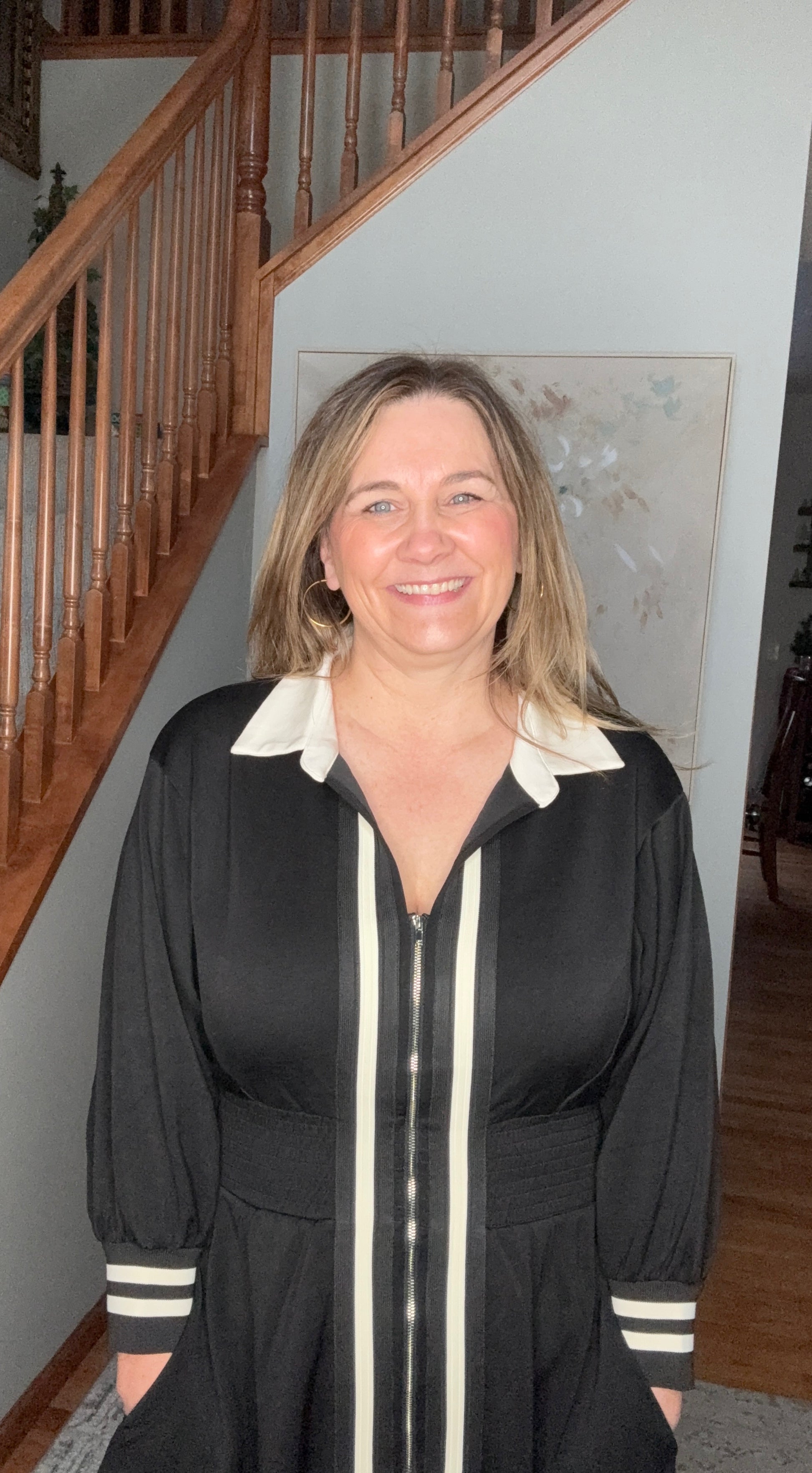 Woman standing in a home setting with a staircase in the background