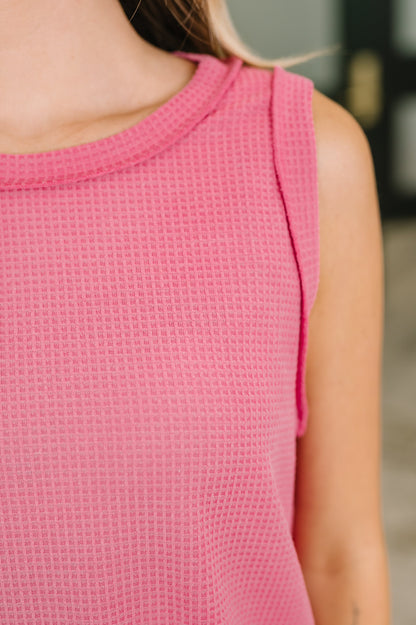 Close-up of a person wearing a pink textured sleeveless top.
