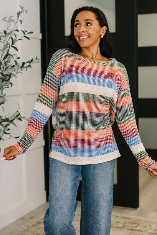 Woman wearing a colorful striped  top and jeans indoors.
