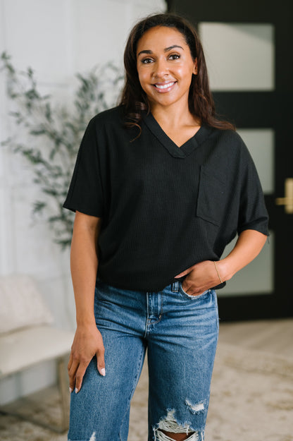 Woman wearing a black shirt and blue jeans standing indoors.