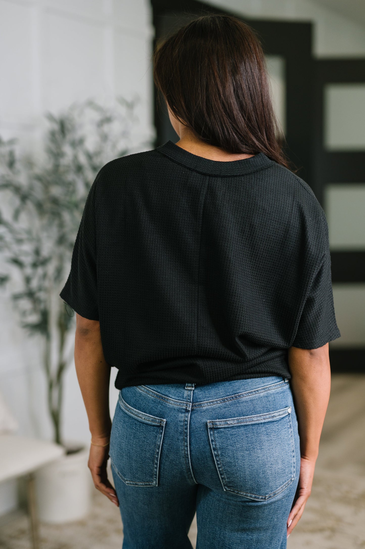 Person wearing a black oversized shirt and blue jeans in an indoor setting