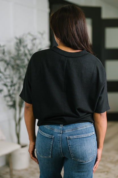 Person wearing a black oversized shirt and blue jeans in an indoor setting