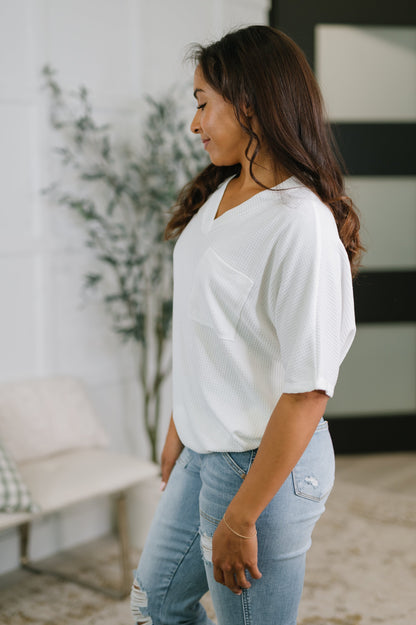 Woman wearing a white top and light blue jeans in an indoor setting