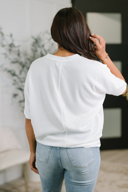 Person wearing a white sweater and light blue jeans indoors.