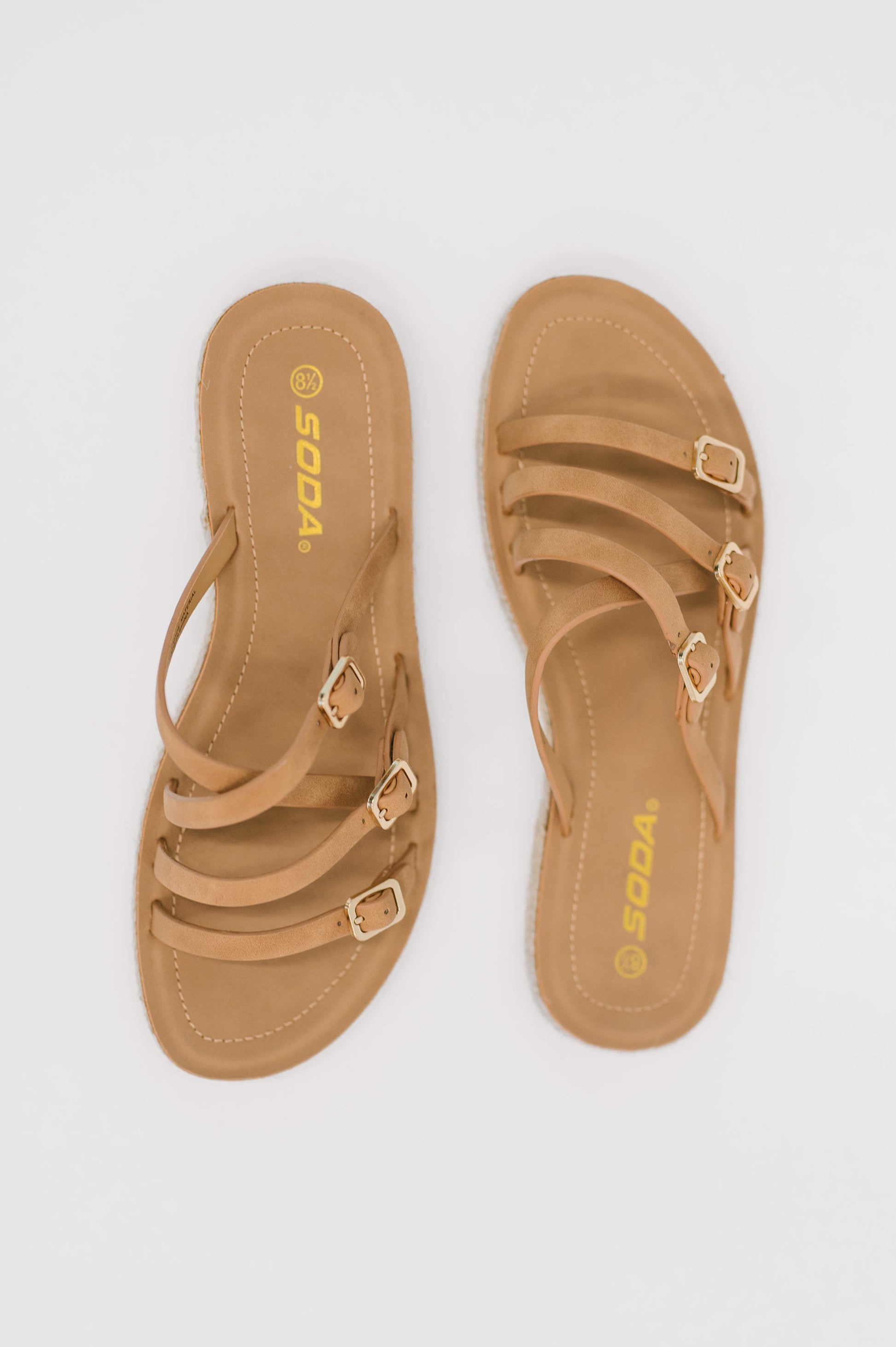 Pair of tan sandals with gold buckles on a white background