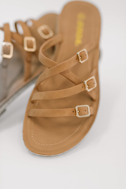 Tan sandal with multiple straps and buckles on a light background