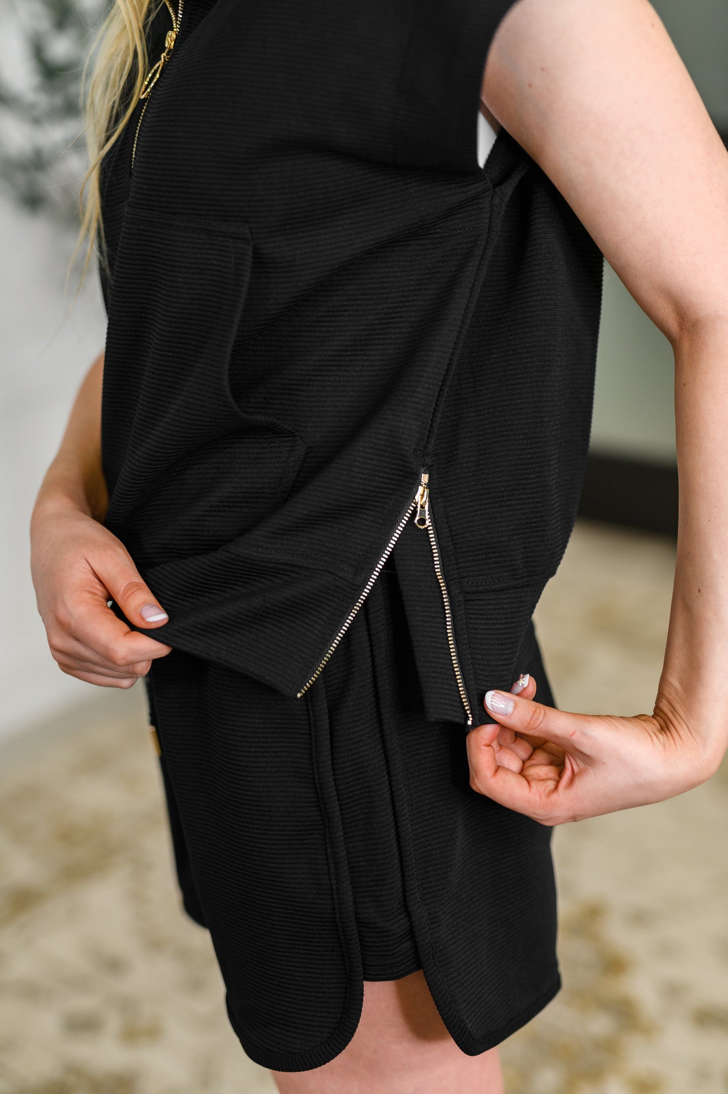 Black sleeveless dress with a zipper detail on a blurred background