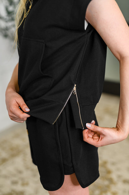 Black sleeveless dress with a zipper detail on a blurred background