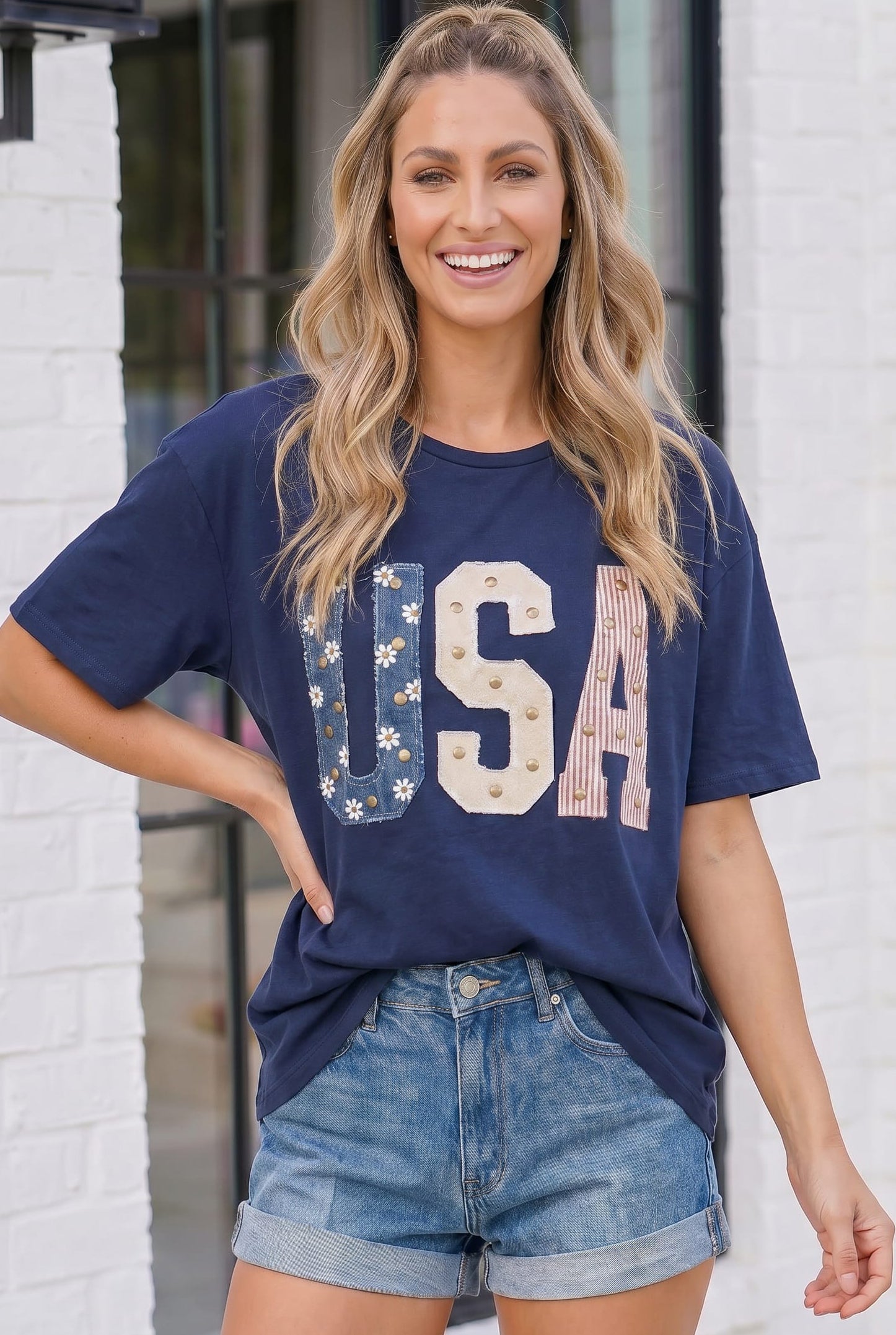 Woman wearing a navy blue 'USA' t-shirt with floral designs outdoors.