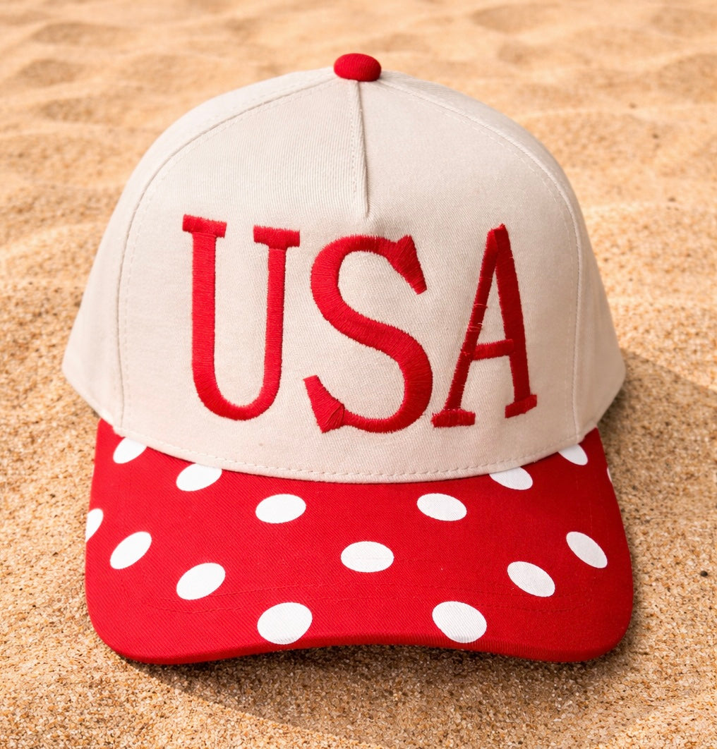Cap with 'USA' on a red and white polka dot visor on sand
