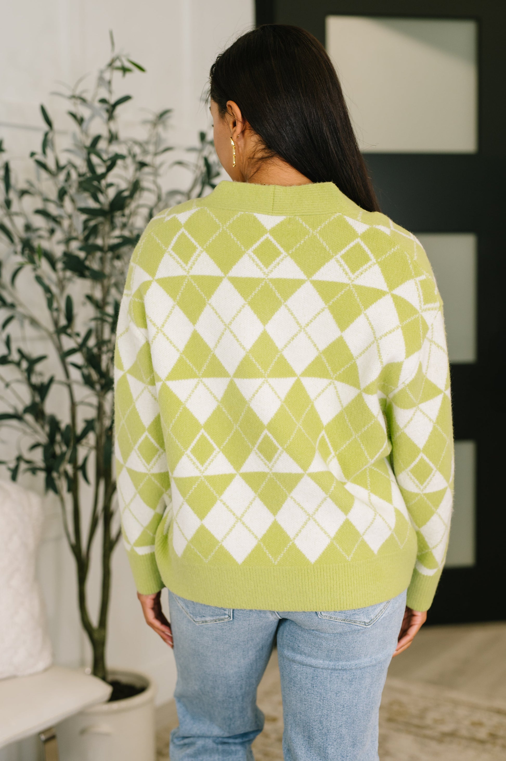 Person wearing a green and white patterned sweater in an indoor setting