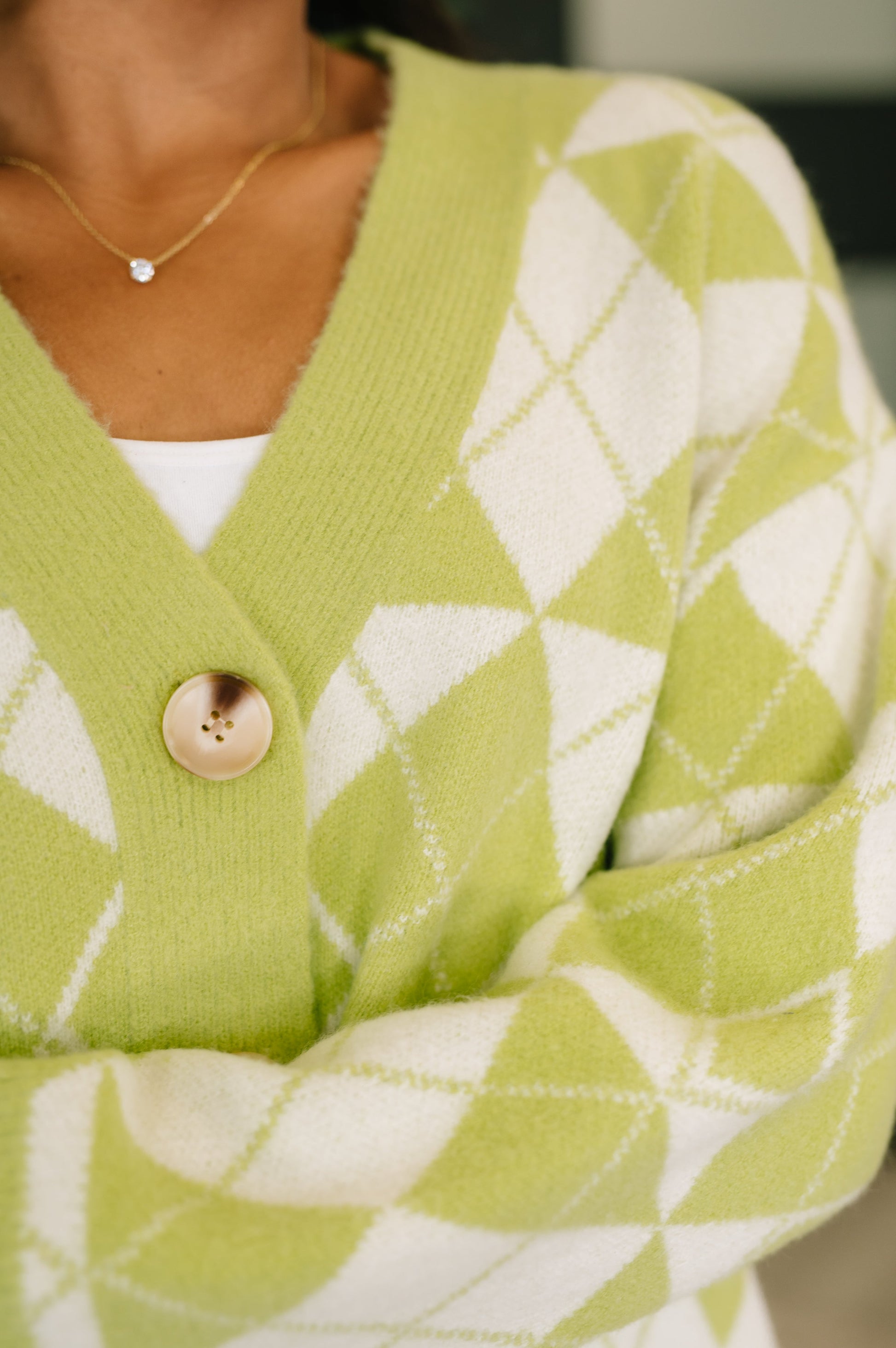 Green and white patterned cardigan with a close-up on a button.