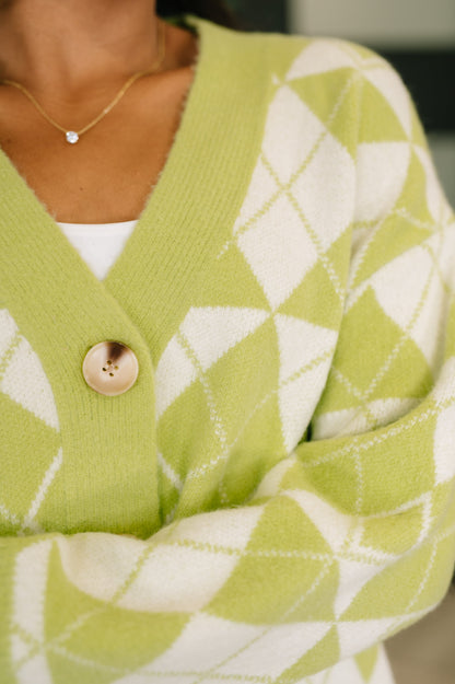 Green and white patterned cardigan with a close-up on a button.