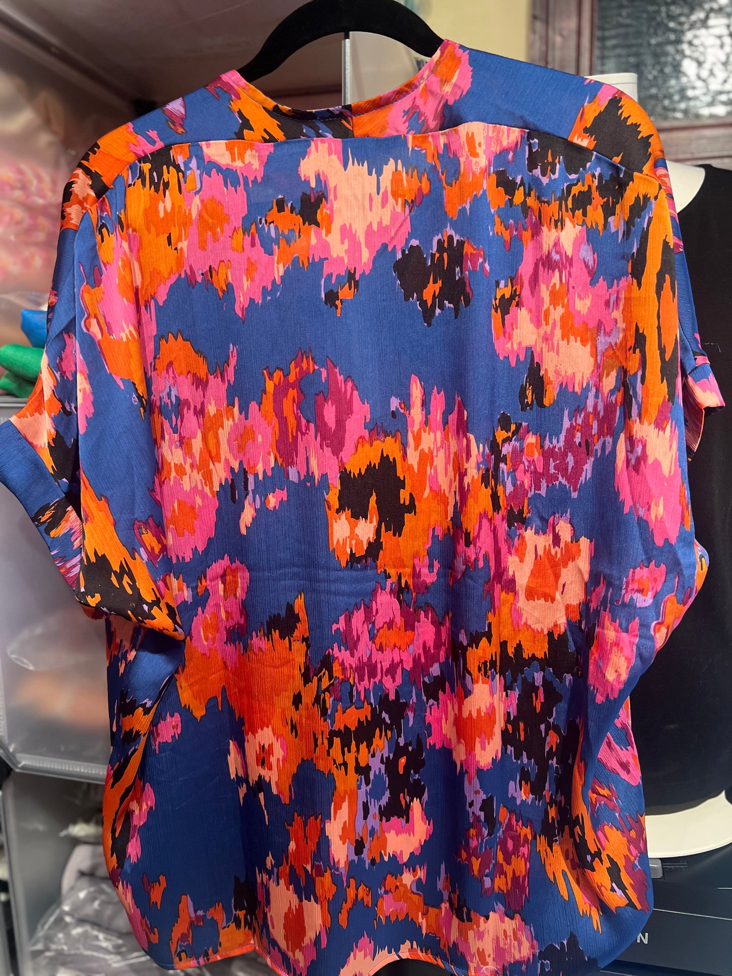 Colorful patterned top on a hanger with a blurred background